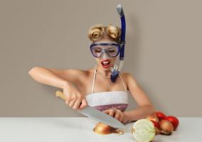 Mujer cortando cebolla llevando gafas de buceo