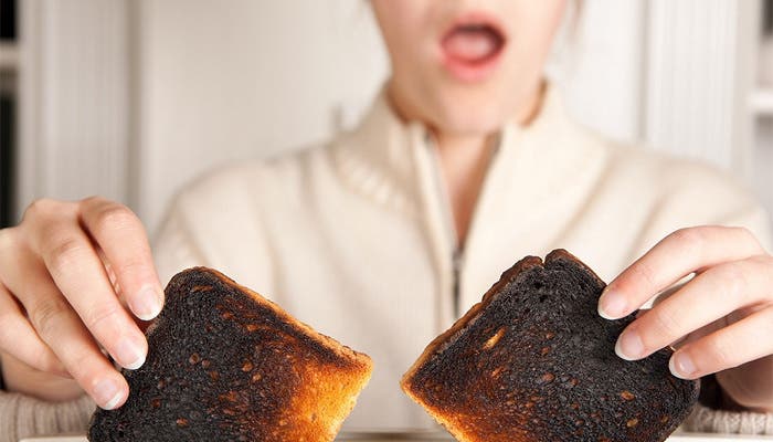 Mujer sostienen sorprendida un par de tostadas quemadas